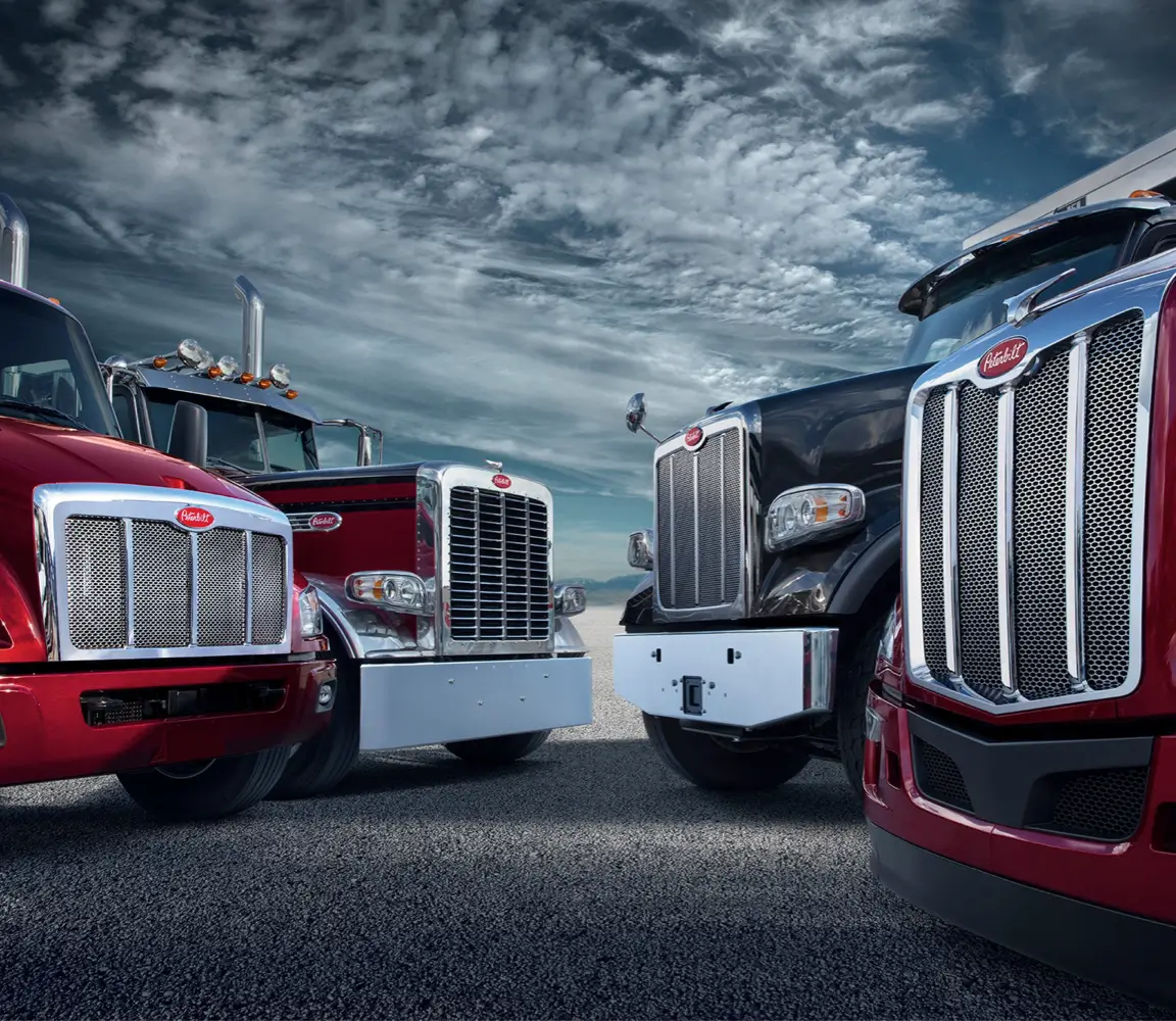 A fleet of trucks wait under a cloudy sky